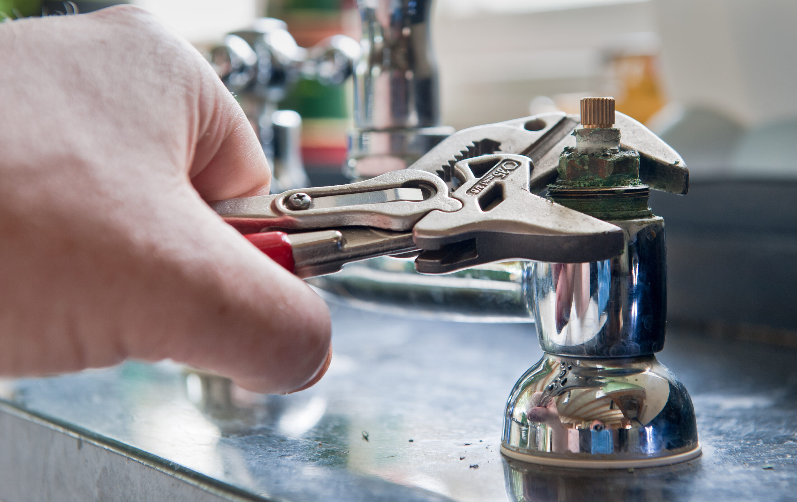 Plumber’s hand fixing a faucet with a wrench