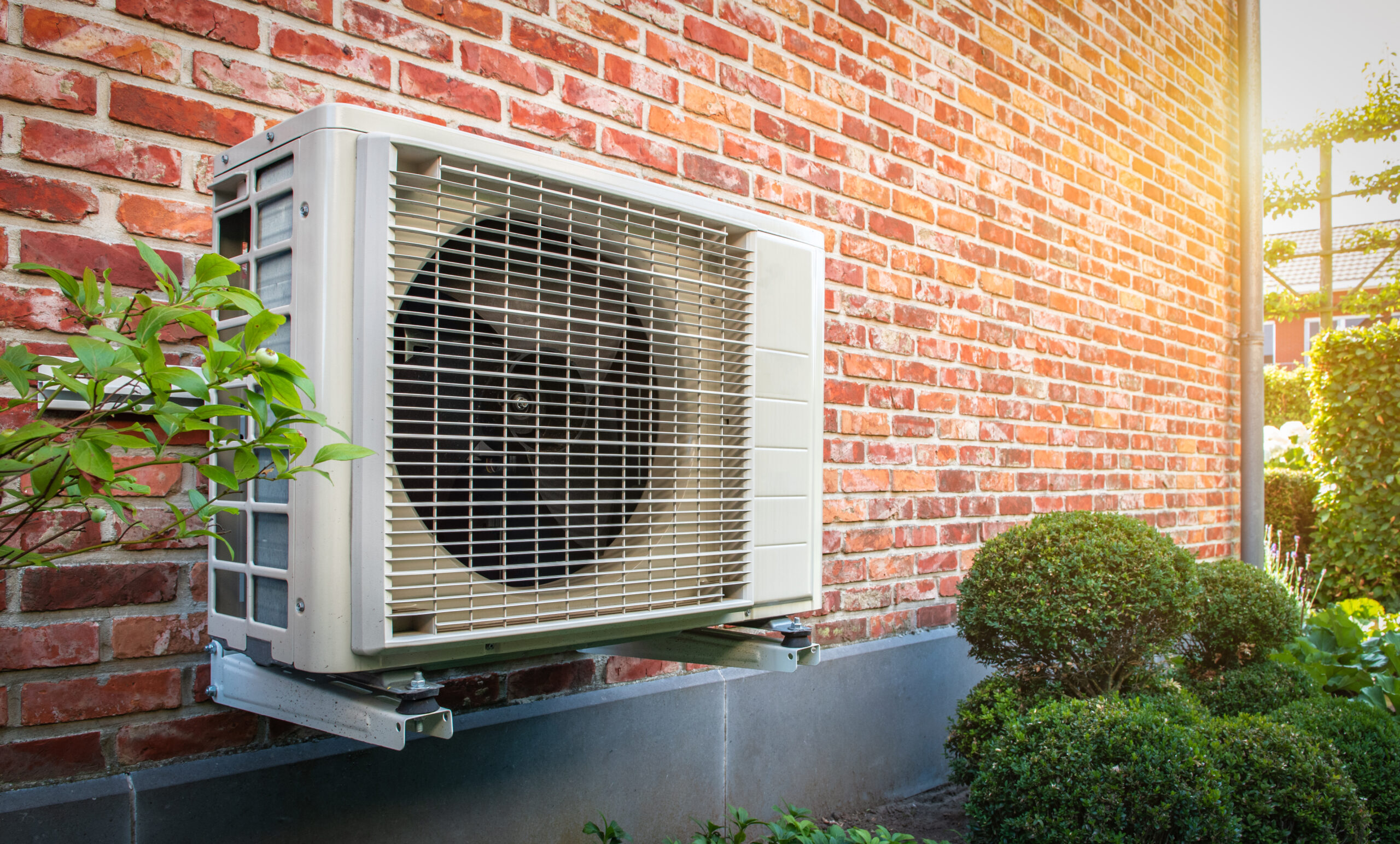 Heat pump mounted on the brick wall of Michigan home.